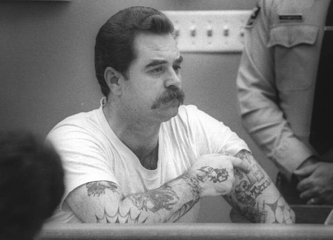 In a July 1988 photo, Dennis Webb points to a tattoo that marks his first murder. He claimed to have murdered five people before being convicted of the murder of John and Lori Rainwater of Atascadero.