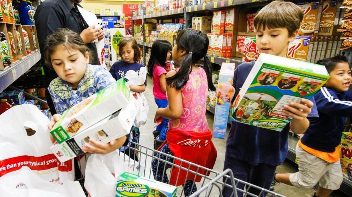A group of C.L. Smith Elementary school first-graders load up a cart with cereal as they shopped for food to donate to the Food Bank Coalition of San Luis Obispo County in April 2016. ASAP Movers is hosting a food drive to benefit the Food Bank this weekend.