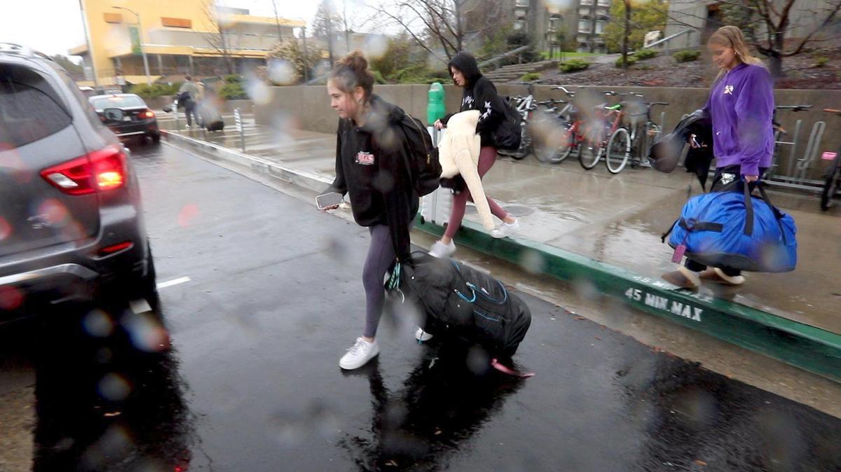 With classes and finals moving online due to coronavirus restrictions some Cal Poly students are heading home to finish the quarter there. From the left Claire Gunness and Skyler Bonanno walk to their Uber ride. at right Cassie Aarestad helps carry luggage.