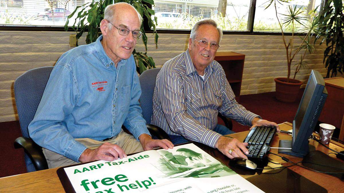 The AARP Foundation Tax-Aide of San Luis Obispo County is offering free tax preparation assistance for 2022, starting Feb. 1, and appointments can be booked now. In this file photo, Jerry Winkenbach, left, and Don Gore in Grover Beach with the AARP Tax-Aide poster used to promote the service.