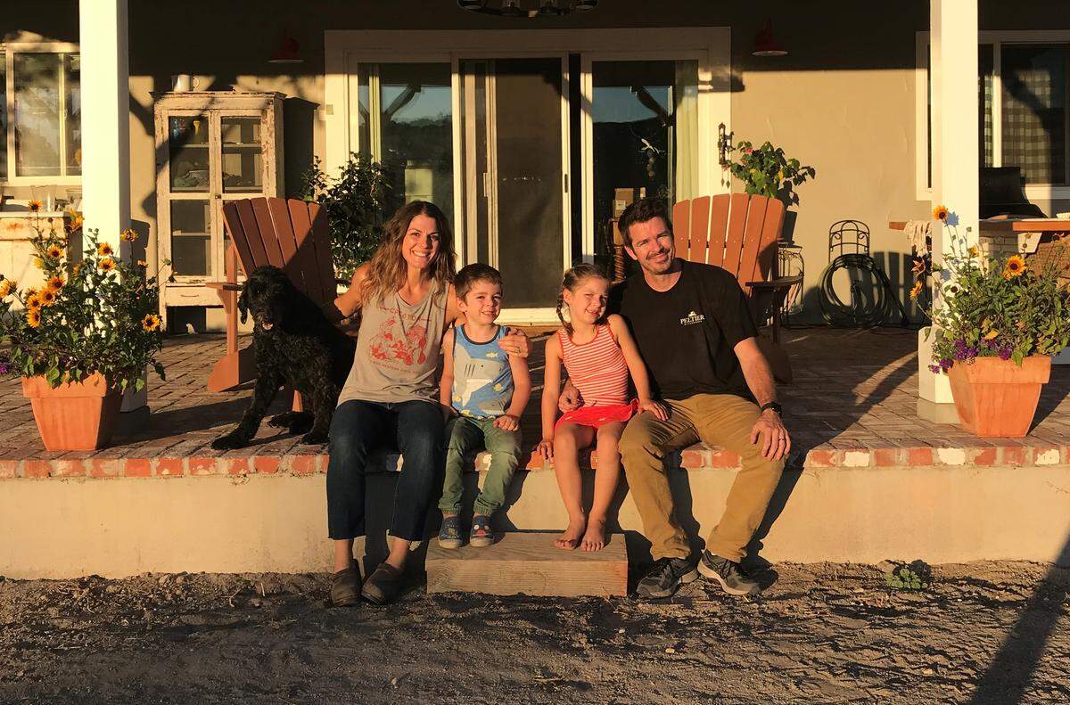 Marisa and Adam Peltier sit with their dog and two children on the porch outside their south Atascadero-Santa Margarita home. The couple previously rented a condo from family, which allowed them to save enough money to buy their 2-acre North County property.