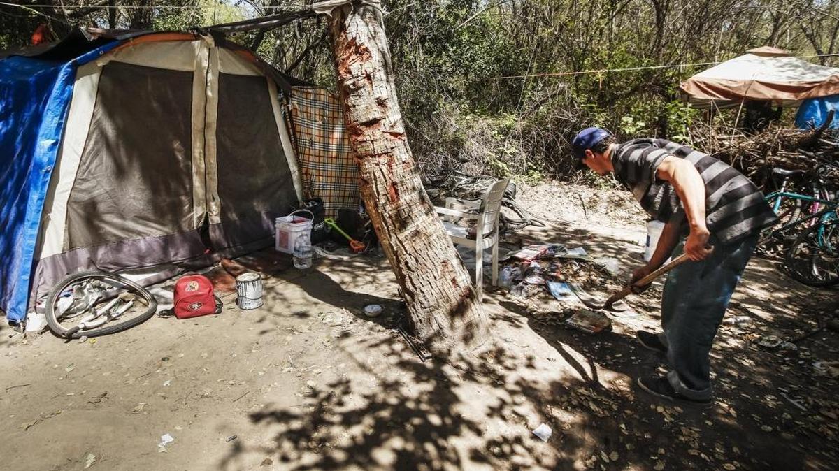 An unidentified man cleans up around his living area at a Grover Beach homeless camp that is being cleared out along North Fourth Street.
