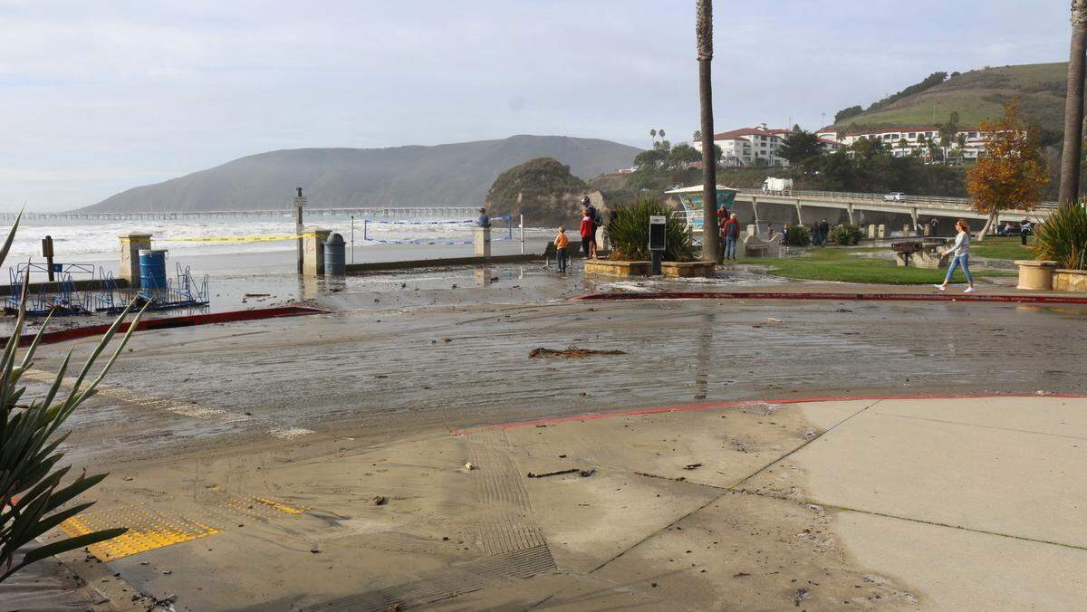 High surf runs all the way up Avila Beach to the sidewalk as visitors take in the sight on Thursday, Dec. 28 2023.