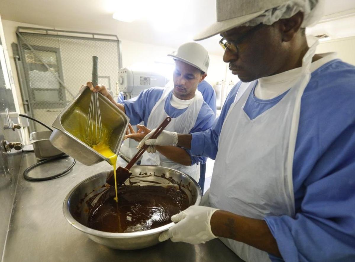Sherman August, back, and Marc Collier prepare the batter for a flourless chocolate cake as part of the California Men’s Colony’s culinary arts program.