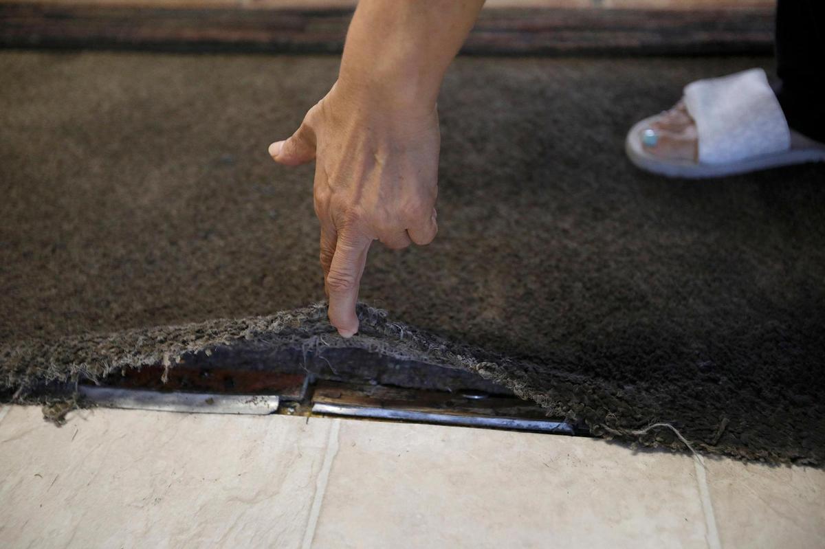 Blanca’s Oceano living room carpet is old, dirty and fraying at the edges. She bought a rug to cover the carpet, which is peeling away from the floor underneath.