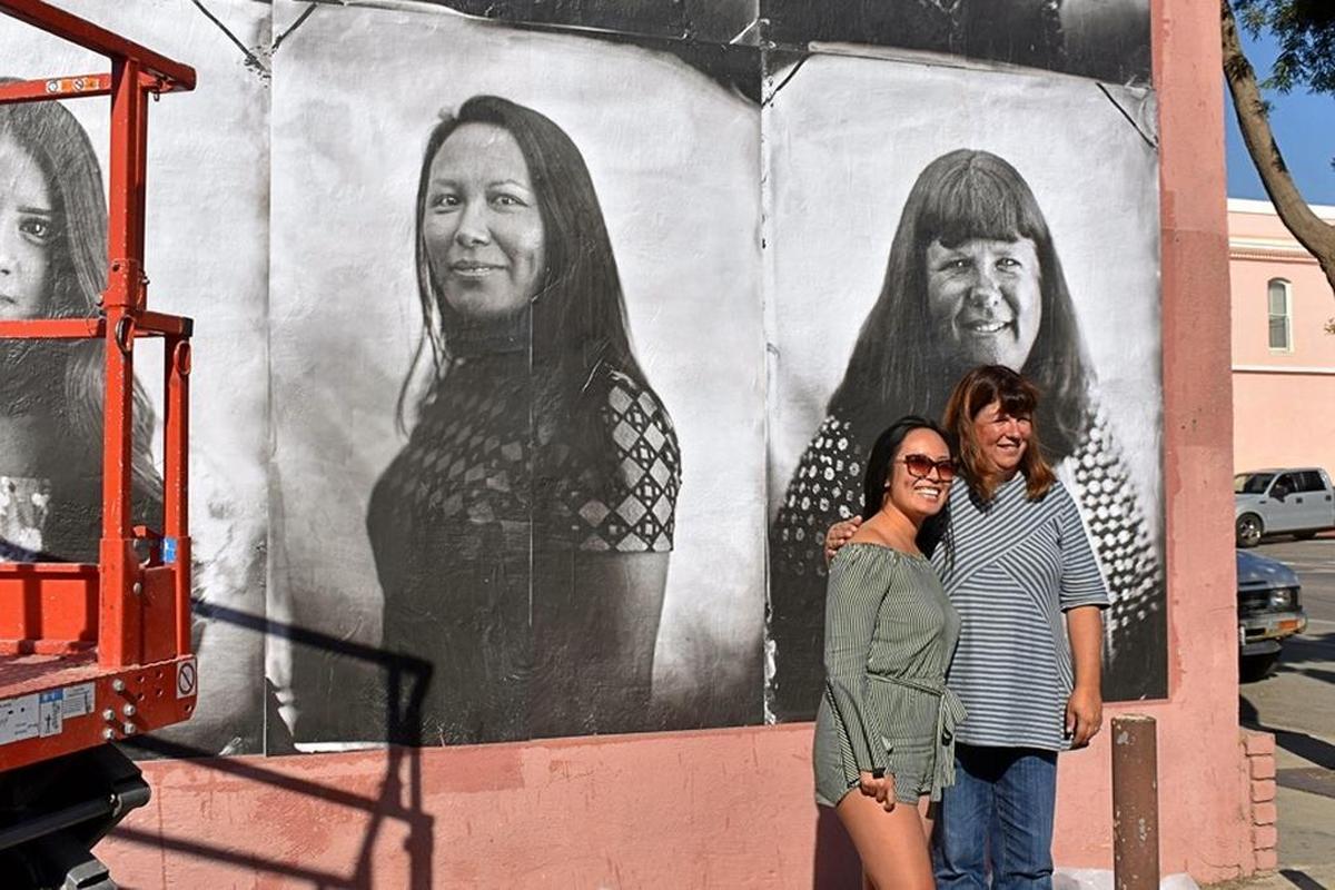 Madison Masatani, left, and Michelle Minetti-Smith pose for pictures in front of a new mural that includes their images in downtown Guadalupe. The installation is on the side of the old Far Western Tavern, which is to become the new home of The Dunes Center. The restaurant, which relocated to Old Town Orcutt several years ago, was founded by Minetti-Smith’s grandparents, Rosalie and Clarence Minetti.