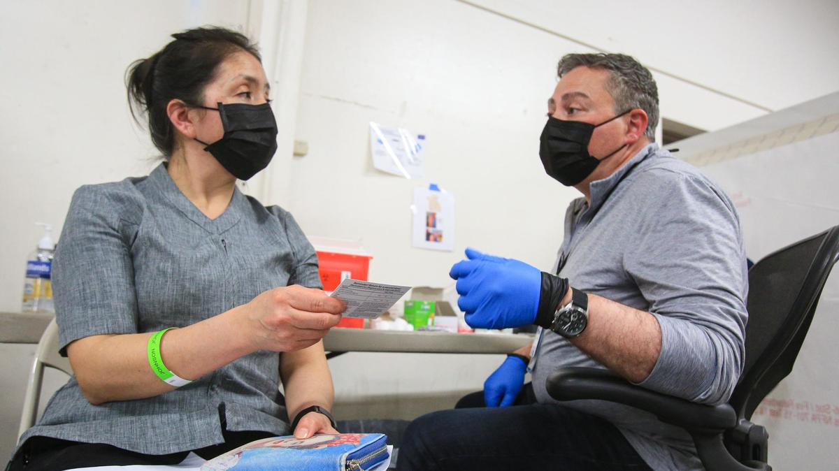 Teresa Allaro talks to Francisco Debs, an emergency medical technician, about information on her coronavirus vaccination card at a San Luis Obispo County Public Health Department clinic for farmworkers at the Paso Robles Event Center.
