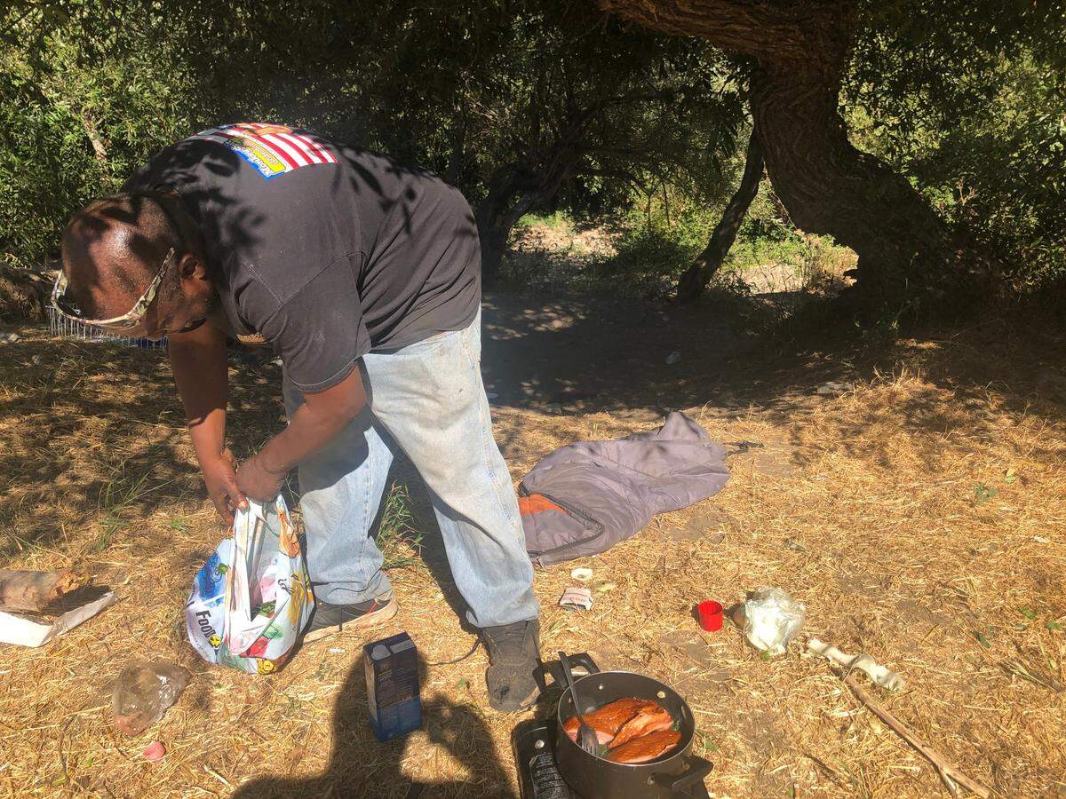 Wayne Cherry cooks up some meat and collard greens on his hot plate near the Bob Jones Trail.