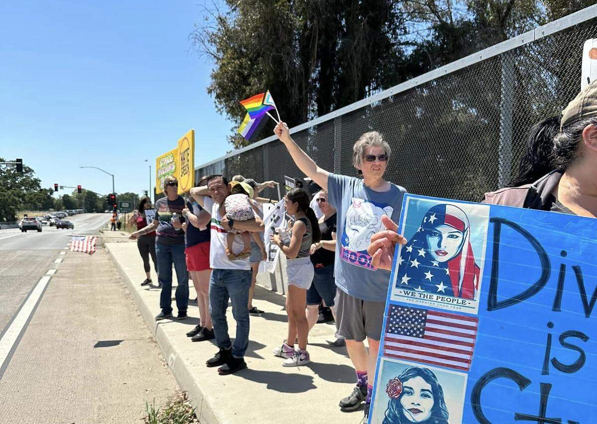 Protesters gather to oppose several men with masks who again held up an “Embrace white pride” flag on the Vineyard Drive Highway 101 overpass on Saturday, May 13, 2023.