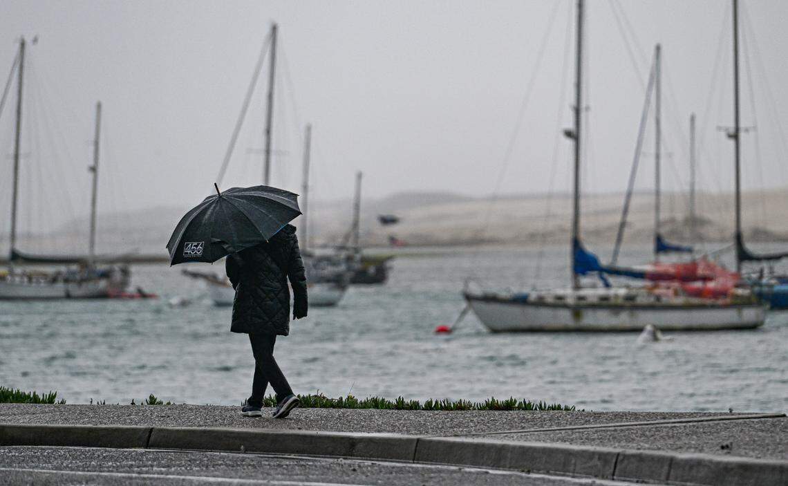 A person walks along the waterfront in Morro Bay during a storm in January 2025.