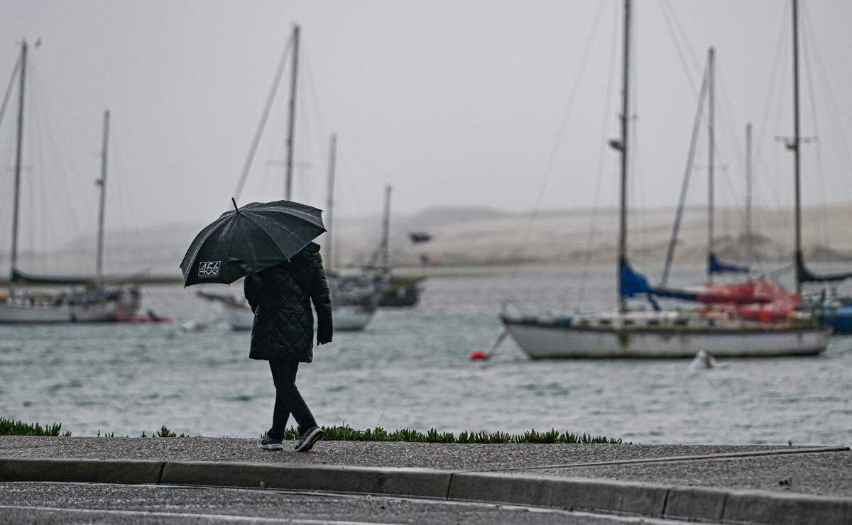 A person walks along the waterfront in Morro Bay during a storm in January 2025.