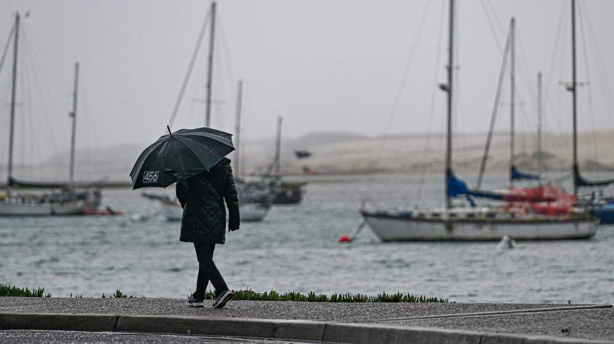 A person walks along the waterfront in Morro Bay during a storm in January 2025.