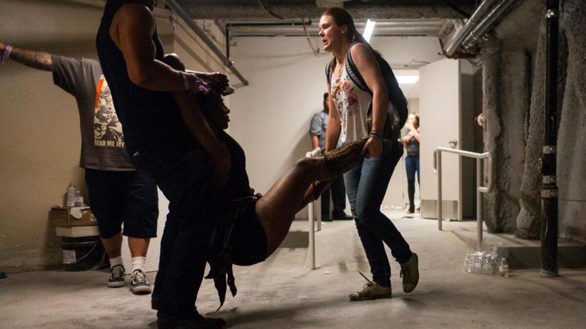People assist a wounded woman Sunday night at the Tropicana in Las Vegas following the mass shooting at a music festival nearby.