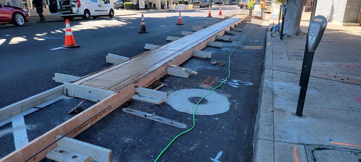 Workers install a median to protect cyclists from parked cars along Higuera Street in San Luis Obispo as part of the Downtown Paving Project.