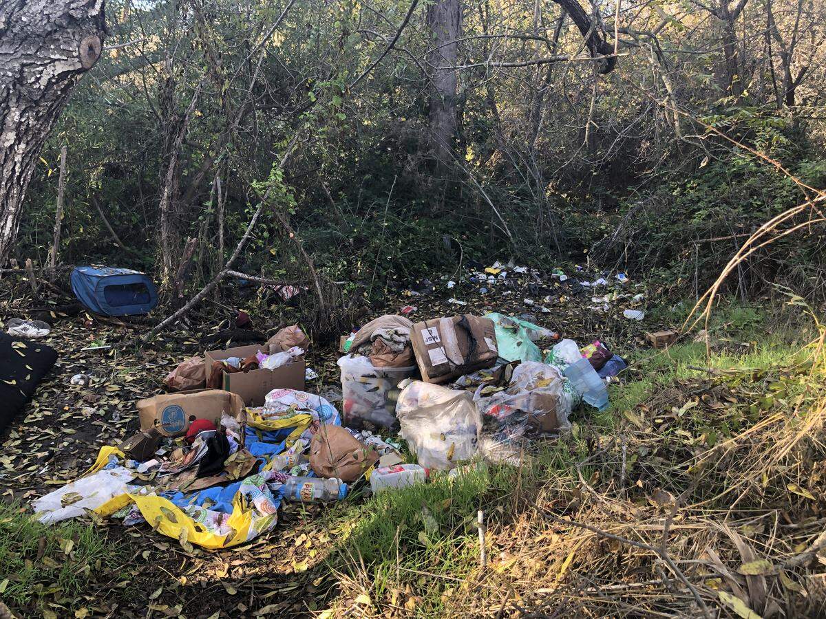 Trash is littered alongside San Luis Creek near Elks Lane at a former homeless encampment.