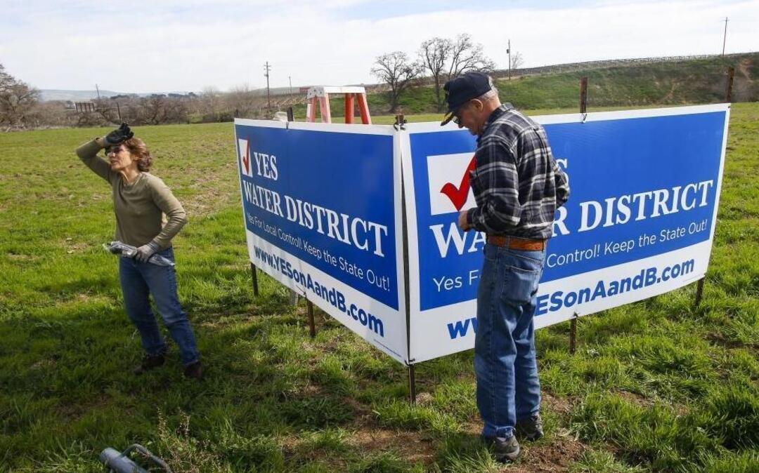 Laurie Gage and Dave King install signs in support of a North County groundwater sustainability agency, which residents voted down in March.