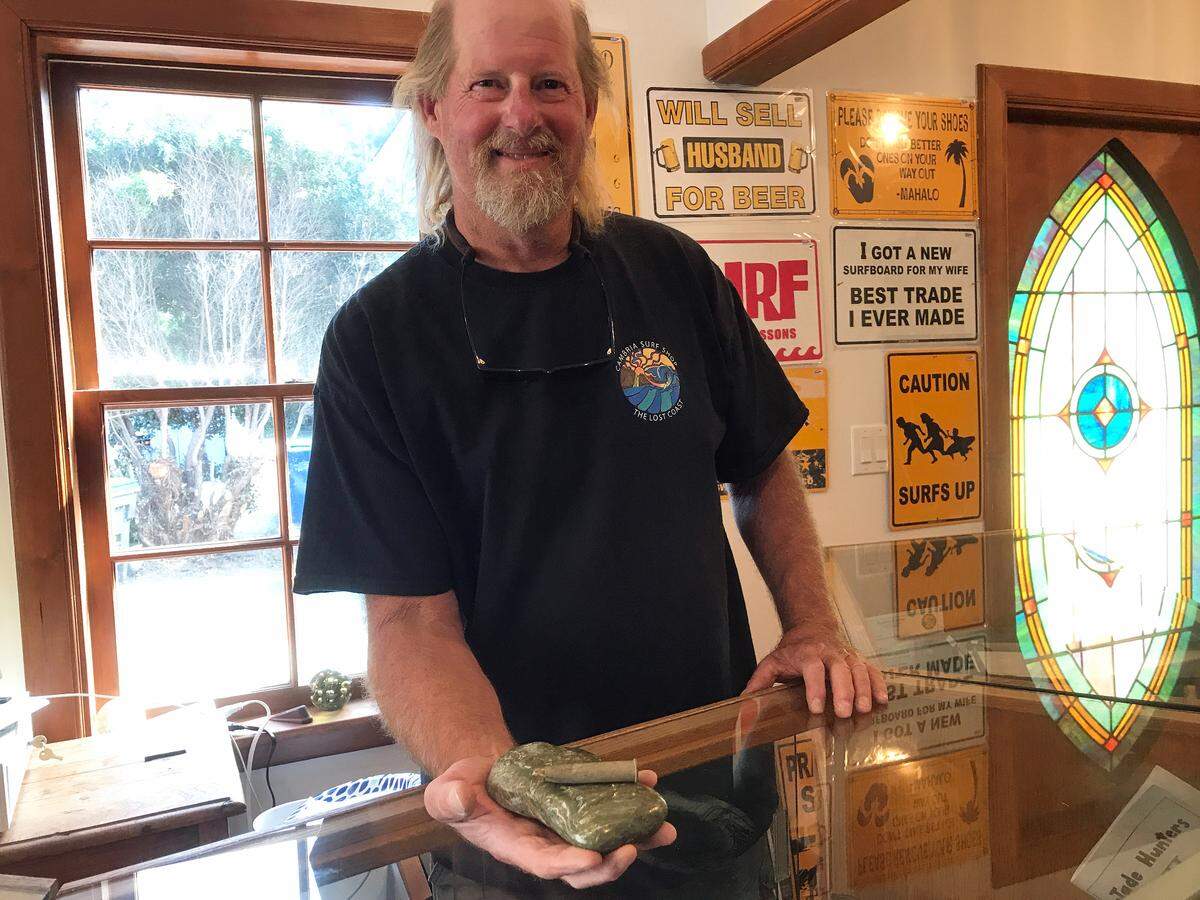 Bill Bookout, owner of the new Cambria Surf Shop, shows off a hunk of jade from Jade Cove and an antique shotgun shell he dug up while redoing the former home’s garden area.