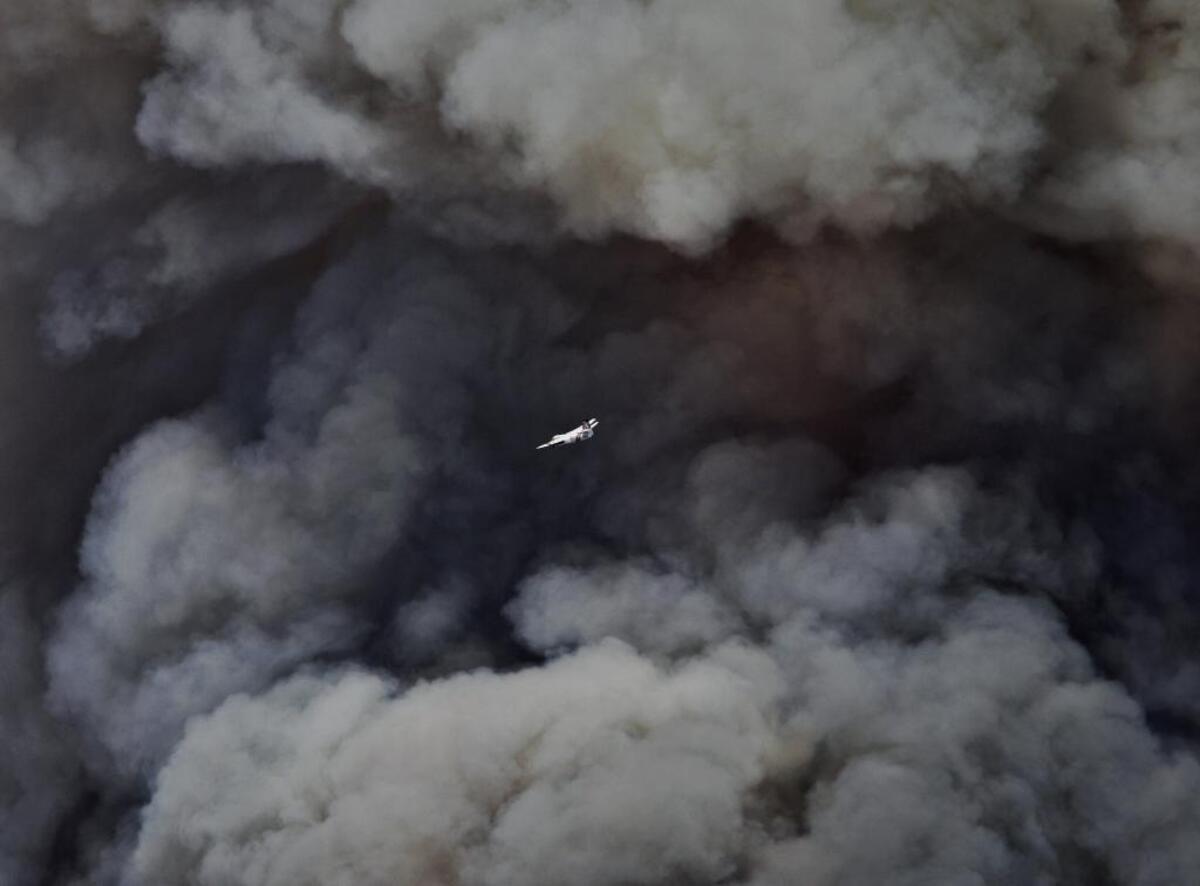 An air tanker flies in front of the plume of smoke rising from the southwest front of the Chimney Fire.