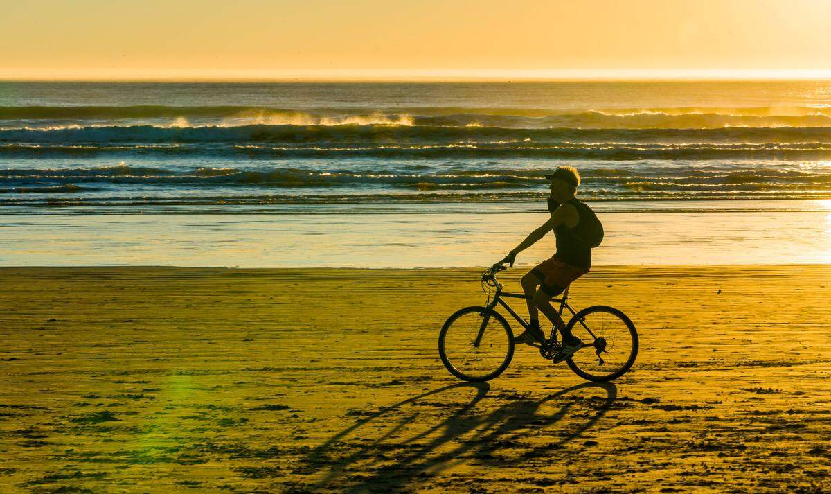 A cyclist rides on the sand in Pismo Beach.