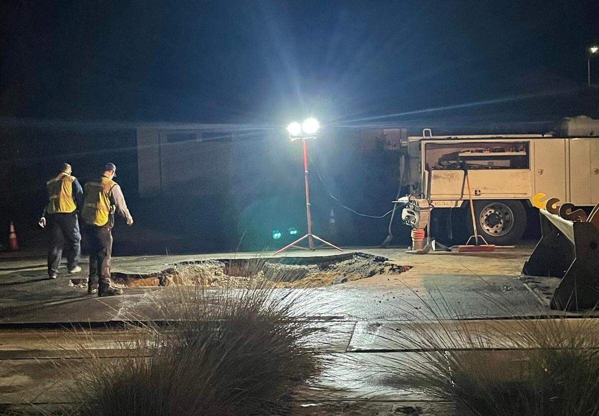 Workers patch a sinkhole that opened up due to a water main break in San Luis Obispo on Nov. 2, 2022.