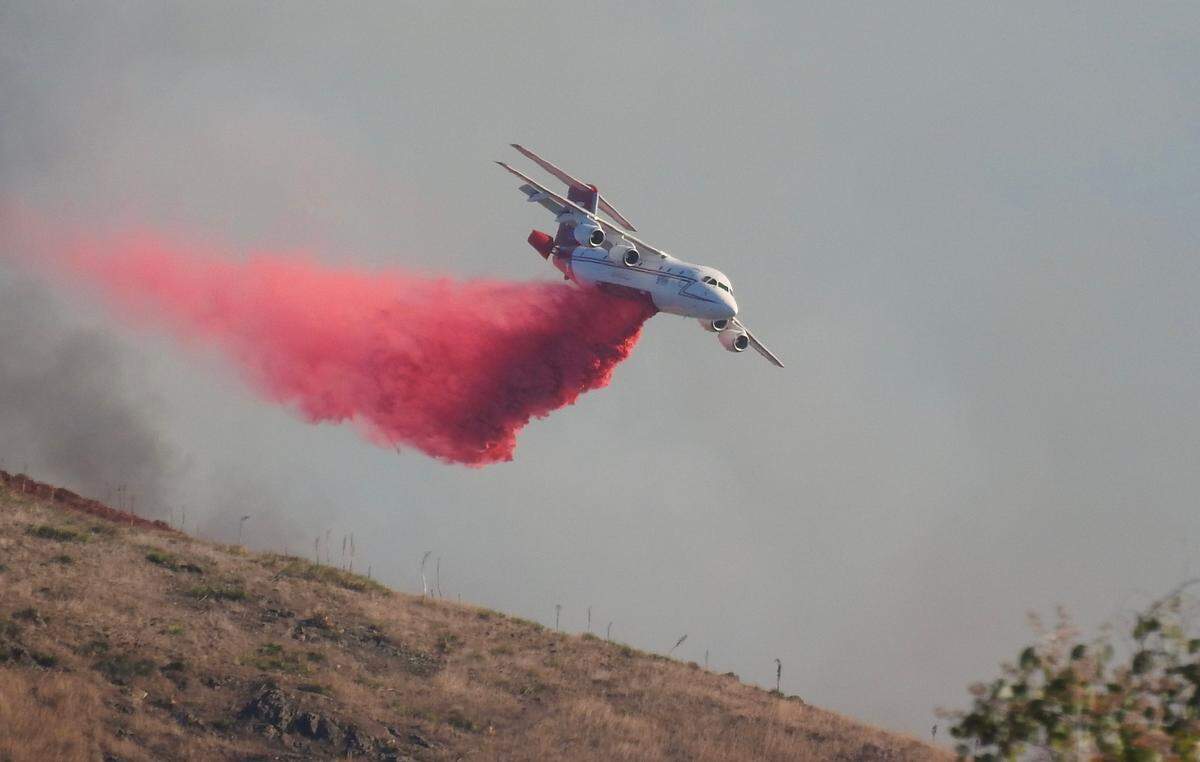 An air tanker drops retardant on a fire burning in the hills behind San Luis Obispo High School on Monday, Oct. 30, 2023.
