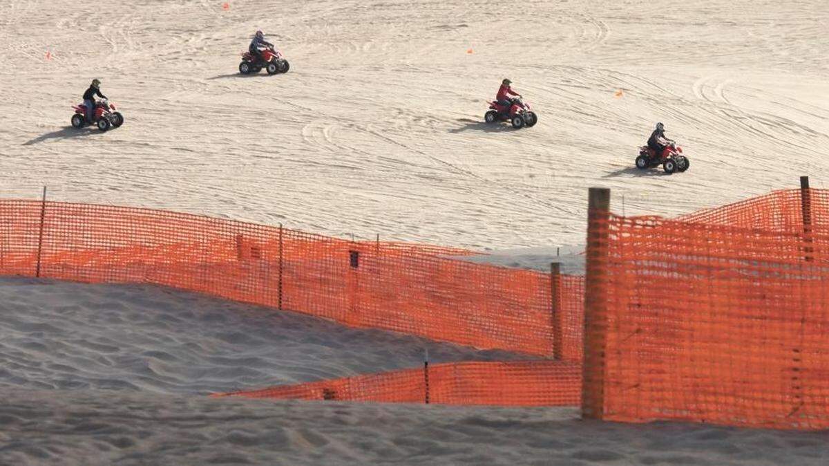 Off-roaders ride at the Oceano Dunes State Vehicular Recreation Area near fencing designed to reduce the spread of dust into nearby communities.