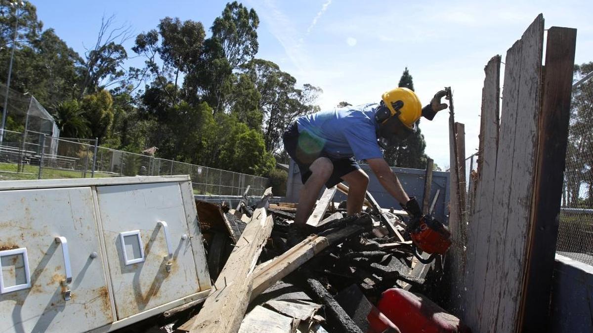 Remains of shed burned in a suspected arson fire Friday are placed in a Dumpster to be hauled away on Tuesday. A crew from San Luis Coastal Unified School District completed the work.