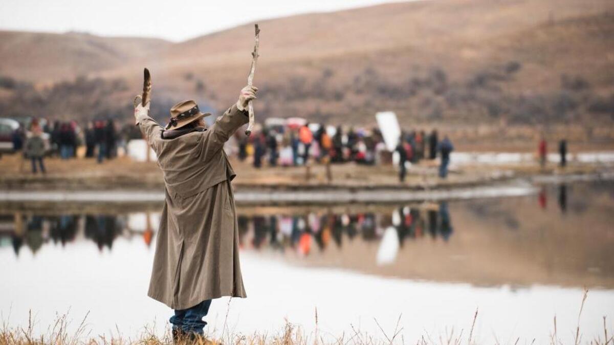 Bill, a Standing Rock Sioux tribal member, stands on the bank of the Cannonball River at Standing Rock Sioux Reservation in North Dakota on Thanksgiving, Nov. 24, his arms spread to show he is unarmed. He’s among the activists who have gathered to protest the Dakota Access Pipeline project.
