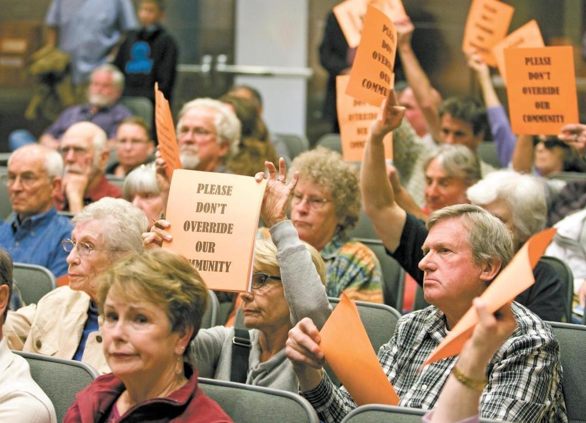 Opponents to the Las Pilitas Quarry project hold signs in silent support of a speaker during a SLO County Planning Commission hearing in Jaunary.