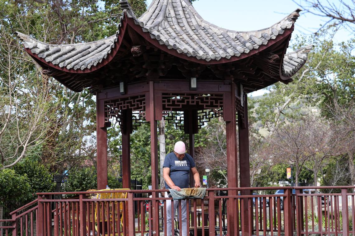 Matthew Googins hangs his clothes out to dry after spending a rainy night under the pagoda at Cheng Park at the corner of Marsh and Santa Rosa streets on March 29, 2022.