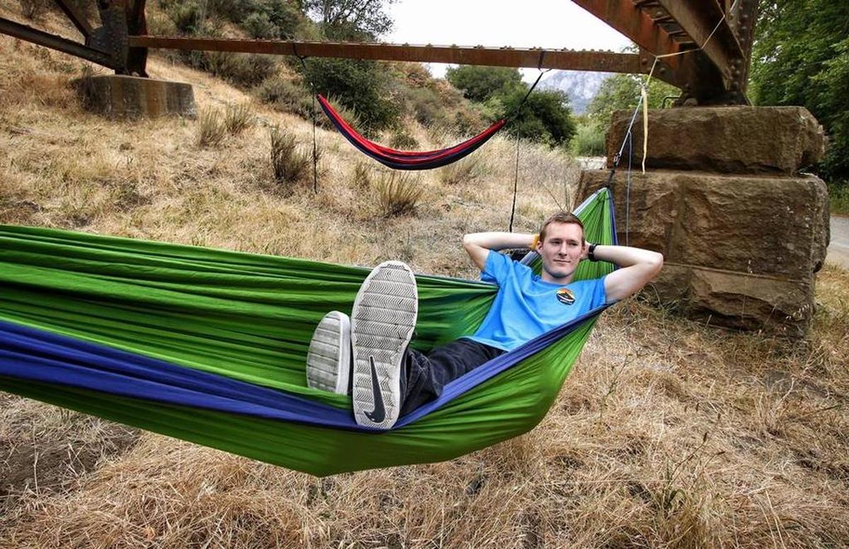 Carter Wilson, president and founder of the Cal Poly Hammock Club, relaxes in his hammock under the train trestle at Cal Poly.
