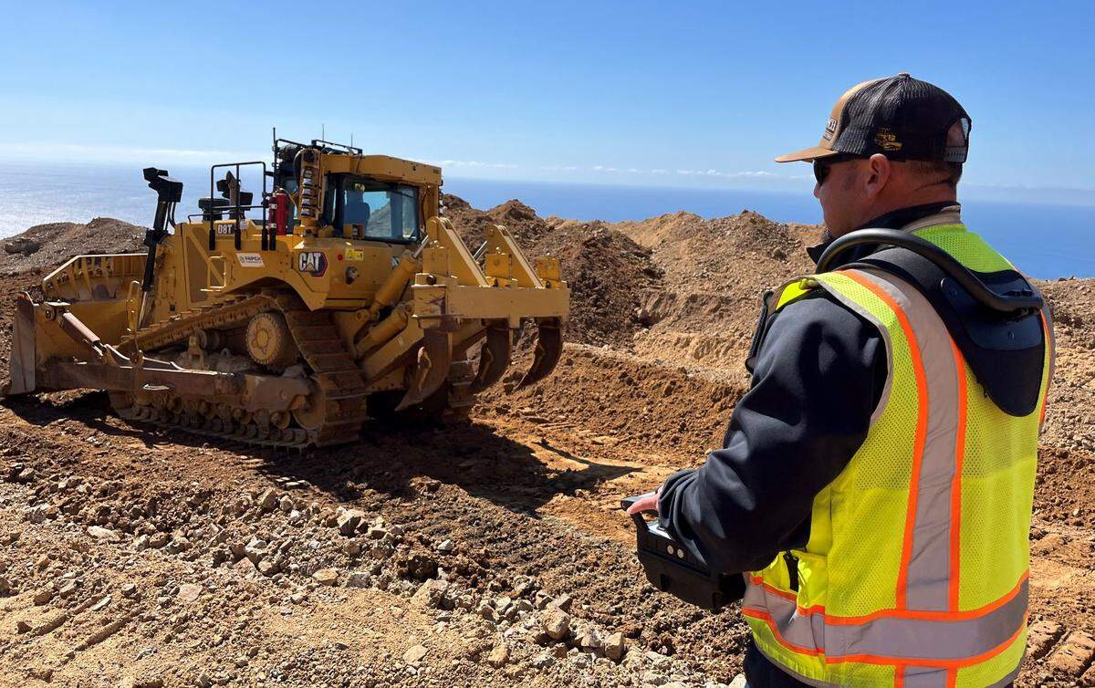 A heavy equipment operator uses a remote control to maneuver an excavator while working at the site of the Regent’s Slide on Highway 1. The innovative technology can both improve productivity and enhance work safety on potentially dangerous slopes.