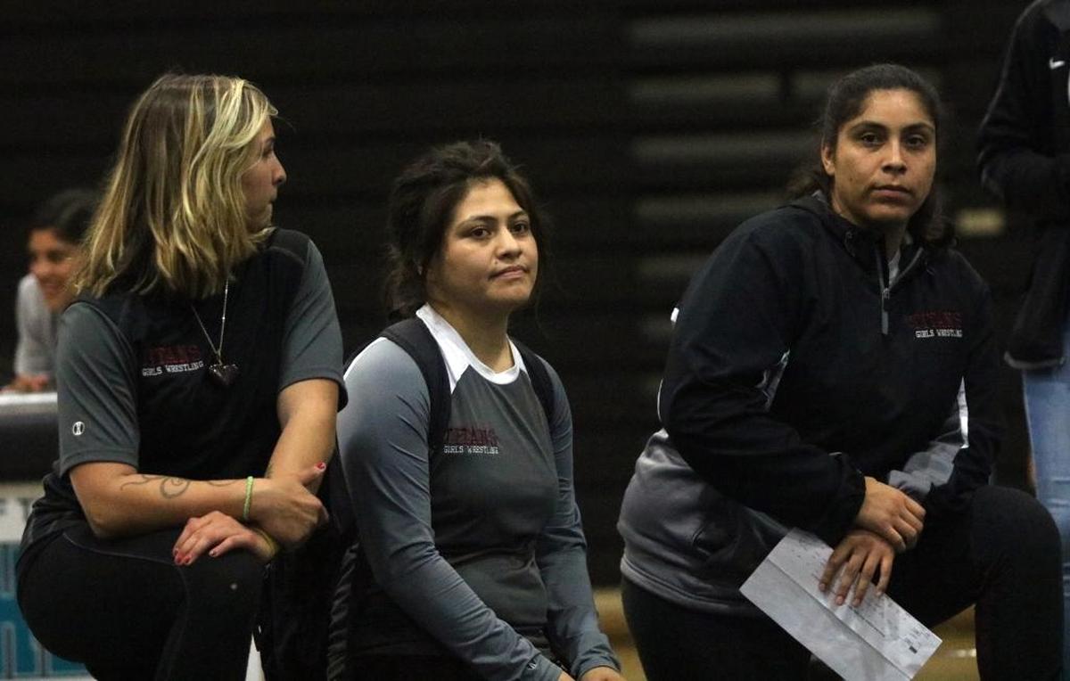 Nipomo High School wrestling coach Marisol Arredondo (center) sits on the mat between assistant coaches Paloma Basulto (right) and Sabreena Shelton during a dual meet at Pioneer Valley High on Jan. 11.