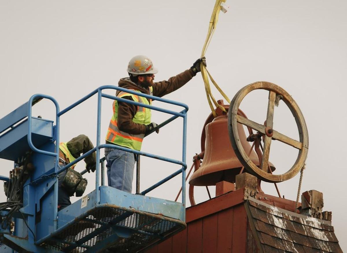 A worker attaches lines to the bell before lifting from the steeple to the ground Monday at St. Stephen’s Episcopal Church in San Luis Obispo.