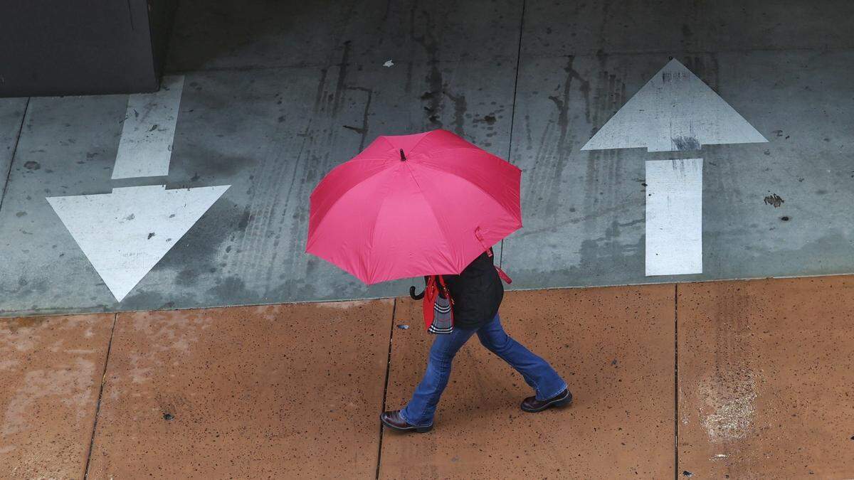 A pedestrian walks in the rain nest to Hotel San Luis Obispo on Dec. 1, 2022.
