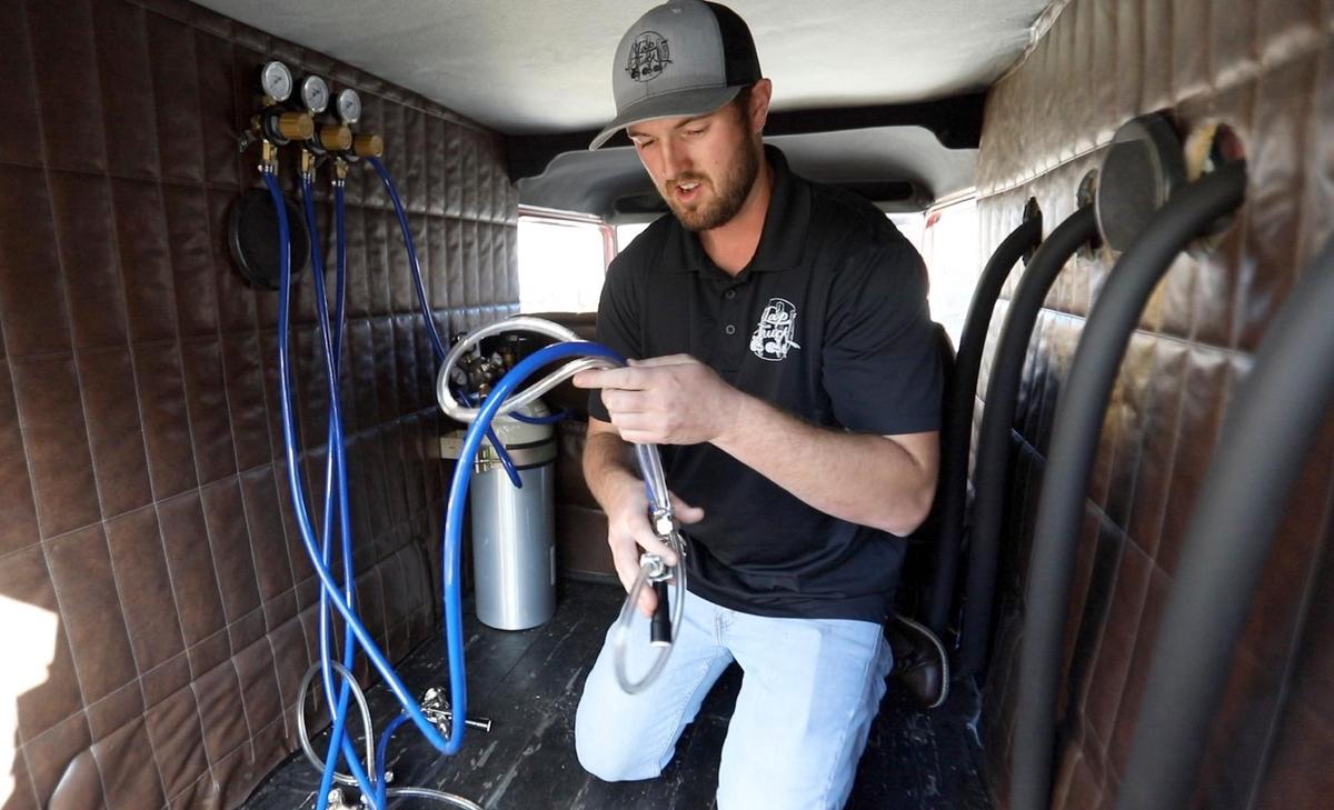 Tyler Steers demonstrates how he taps the kegs inside one of Tap Truck USA’s vintage vehicles.