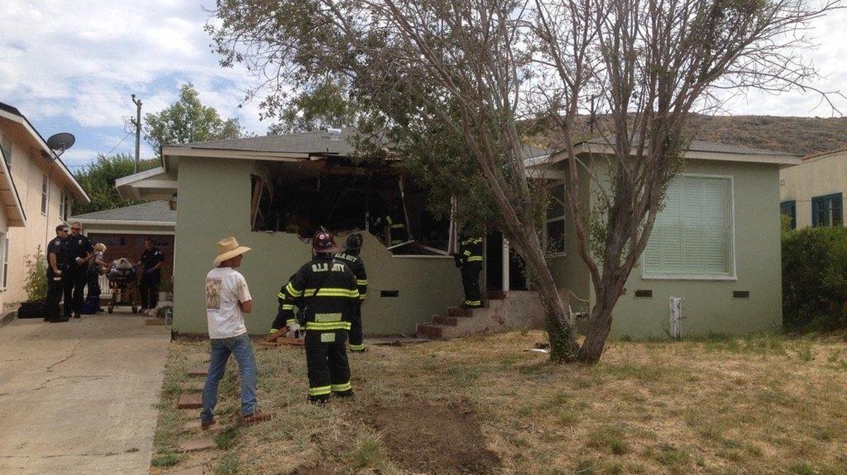 San Luis Obispo firefighters evaluate a home near the intersection of Lawton Avenue and Mitchell Drive where an SUV lost control Tuesday and plowed through the front wall.