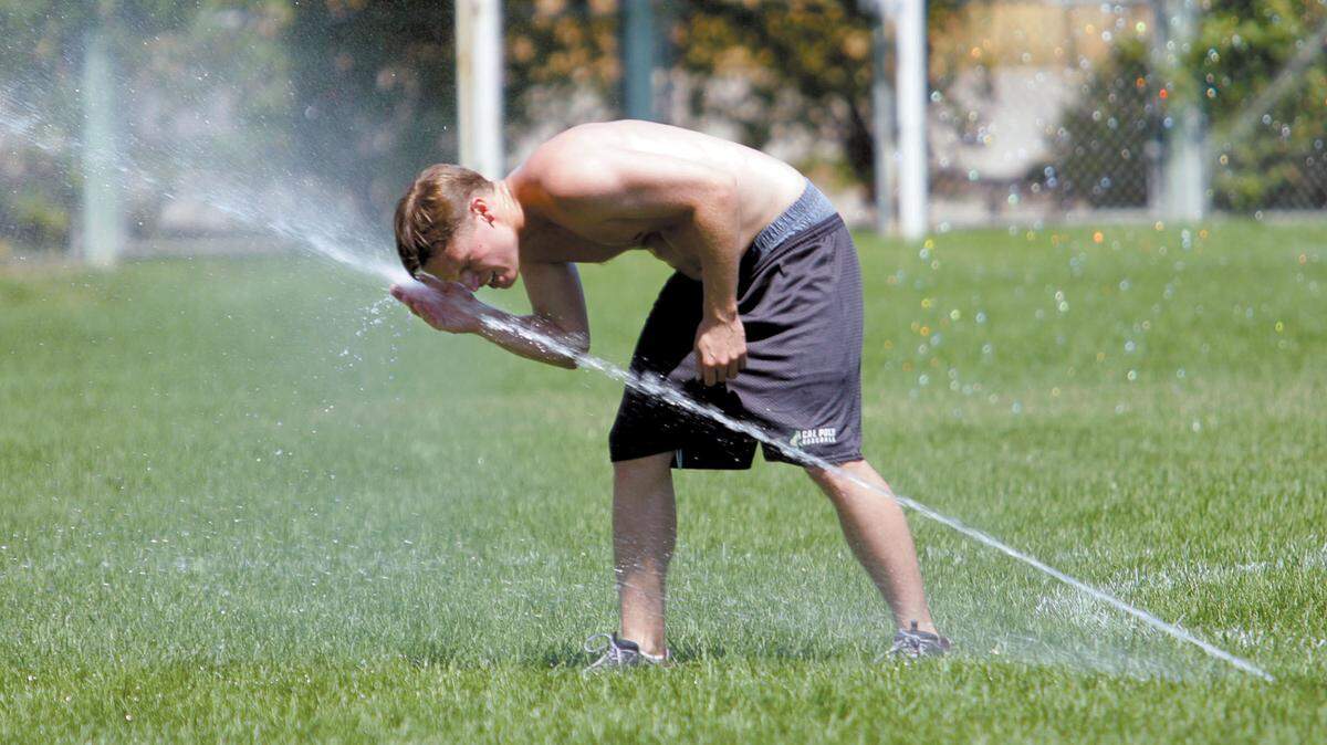 Adam Grenier cools off in the sprinklers as he and a group of co-workers from Applied Technologies Associates played a game of ultimate frisbee at Barney Schwartz Park in Paso Robles. The group meets a couple times a week during lunch to play. Photo by Joe Johnston 8-21-07