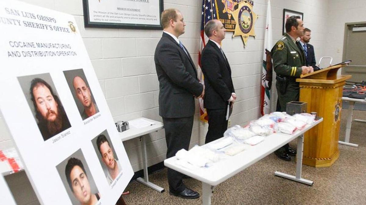 Law enforcement authorities hold a news conference on Aug. 11, 2015, on a drug-trafficking investigation that resulted in the seizure of cocaine, seen on the near table, and guns, on the far table.