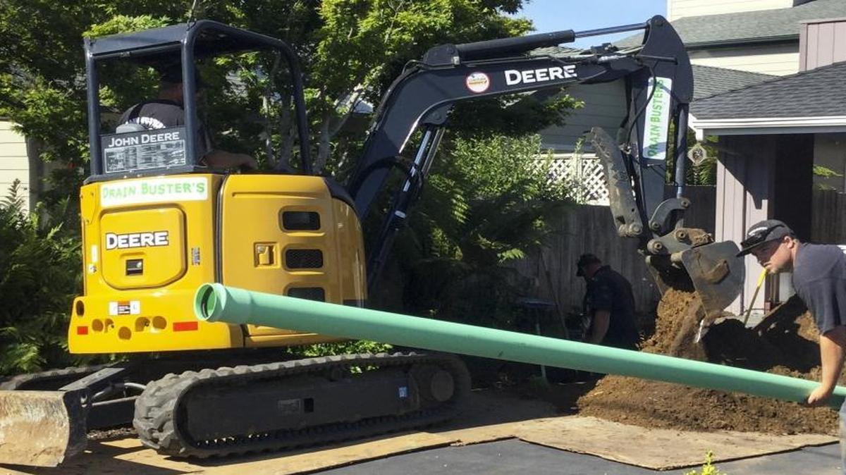 Dillon Macaire with Drain Busters Plumbing sets down pipe that will be used to connect the wastewater from Gary Giannico’s Los Osos home to the county sewer system. Dan Walker operates the tractor.