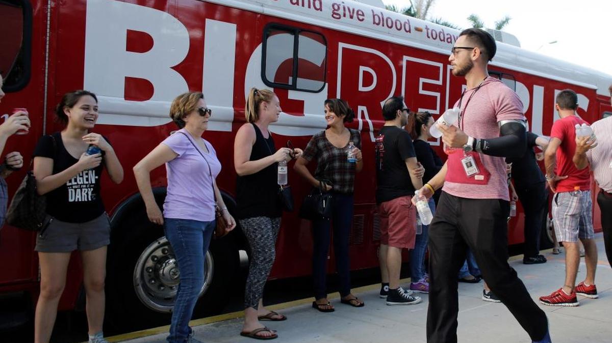 Arturo Roque passes out water to those waiting in line to donate blood in the aftermath of the Orlando mass shooting Sunday in Miami Beach, Fla.