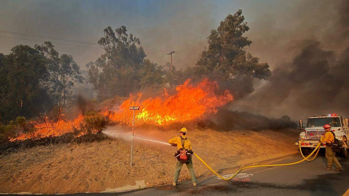 Santa Barbara County Fire Department firefighters battle a roadside fire off Calle Real near Refugio Road in Santa Barbara County. The Alisal Fire had burned 14,500 acres as of Wednesday, Oct. 13, 2021.
