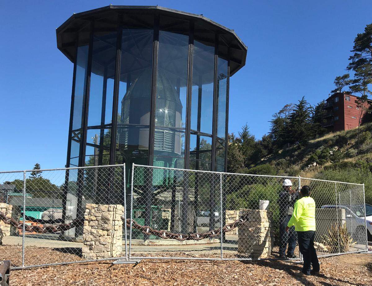 Two fencing installers put the finishing touches on a protective barrier around the circa 1875 Piedras Blancas Light Station First Order Fresnel lens and its glass enclosure on May 11, 2022.