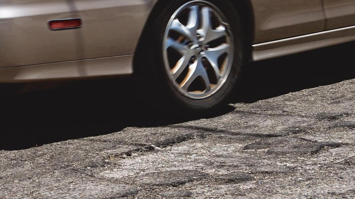 A car drives past a well-worn section of North 13th Street in Grover Beach in June 2015.