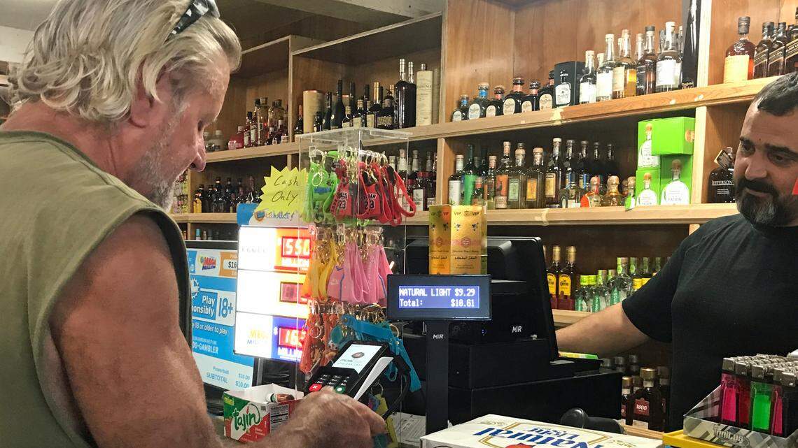 Brad Yetter of Cambria pays Sean Farhoud, general manager of the Cambria General Store on Wednesday, Sept. 13, 2023. Farhoud sold a winning California State Lottery Scratchers ticket on Aug. 9, 2023.