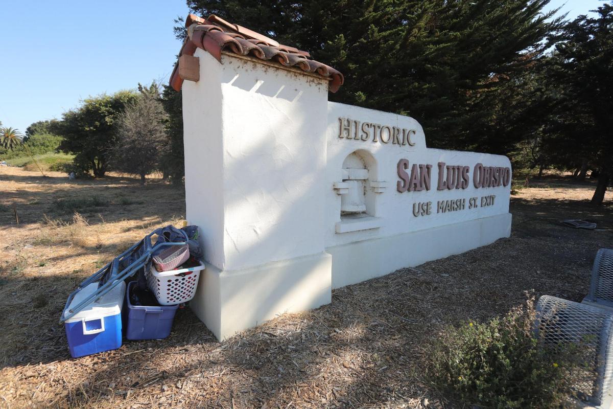 Belongings are stacked along a sign on Highway 101 that welcomes visitors to San Luis Obispo. The city is clearing out 58 homeless camps along the Bob Jones Trail from Prado Road to Los Osos Valley Road, in advance of winter weather.