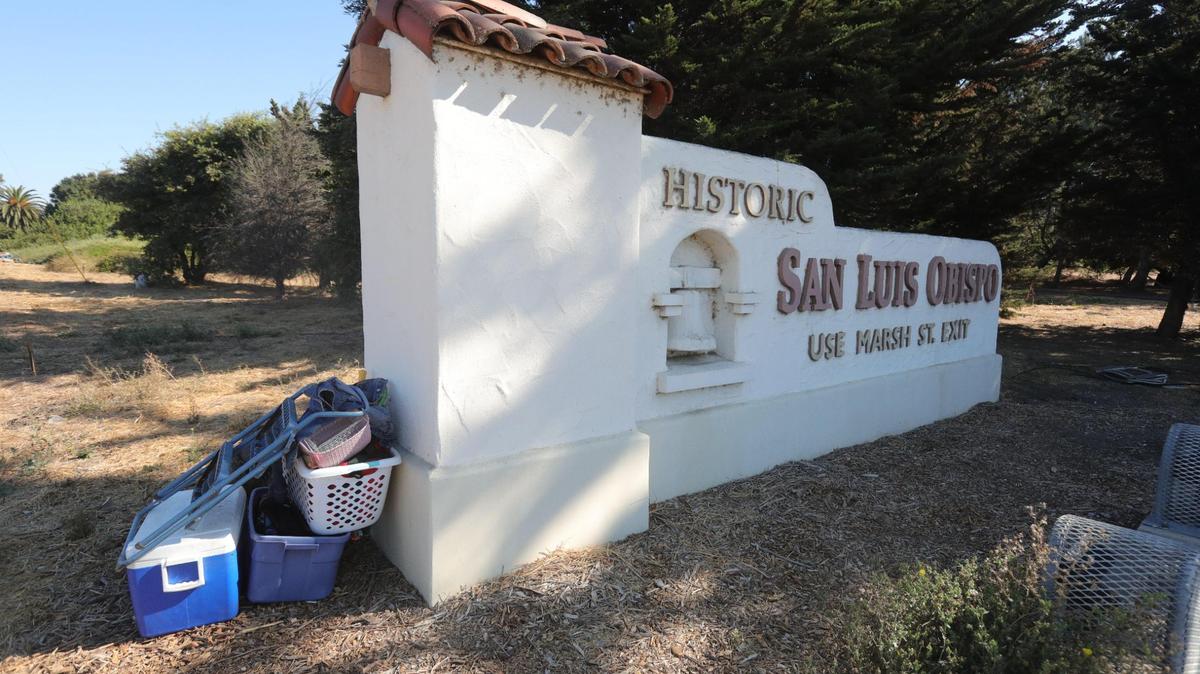 Belongings are stacked along a sign on Highway 101 that welcomes visitors to San Luis Obispo. The city is clearing out 58 homeless camps along the Bob Jones Trail from Prado Road to Los Osos Valley Road, in advance of winter weather.