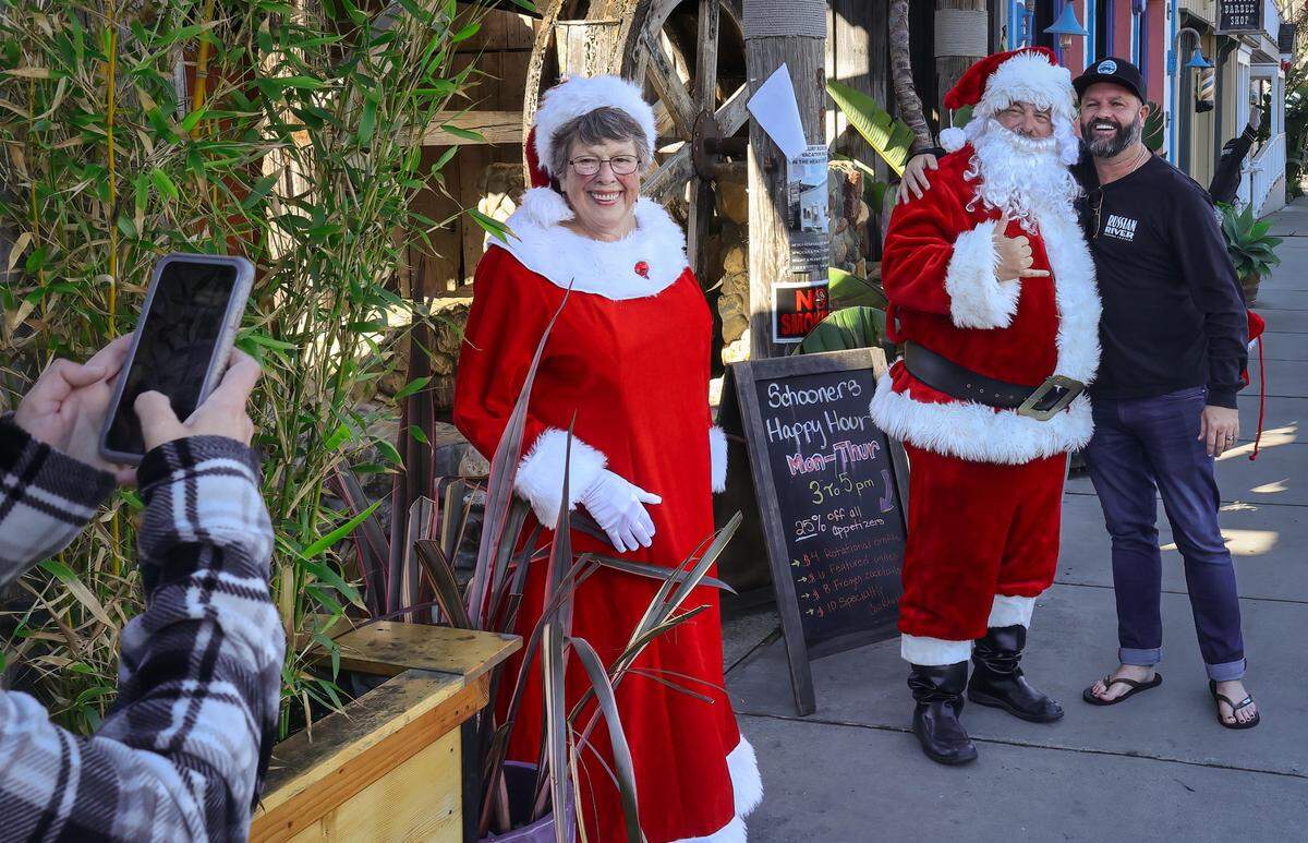 Mrs. Claus (Della Carillo) and Santa (Dave Nygren) pose for a photo with a fan in downtown Cayucos in 2023.