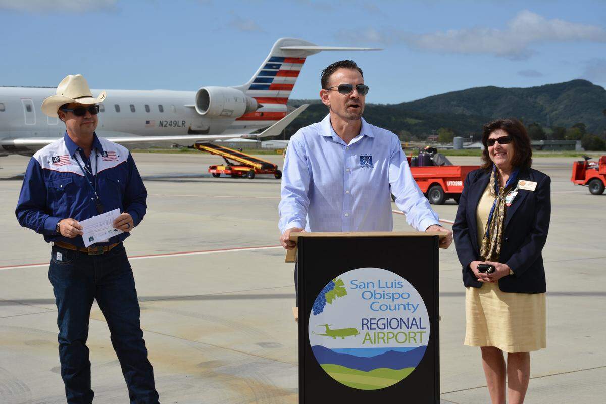 Visit SLO Cal CEO Chuck Davison speaks at the podium, flanked by airport director Kevin Bumen and county supervisor Debbie Arnold after the new connecting flight between Dallas-Fort Worth and San Luis Obispo, California arrived Tuesday. The flight, offering year-round service, now is the farthest east local fliers can travel on a non-stop flight.