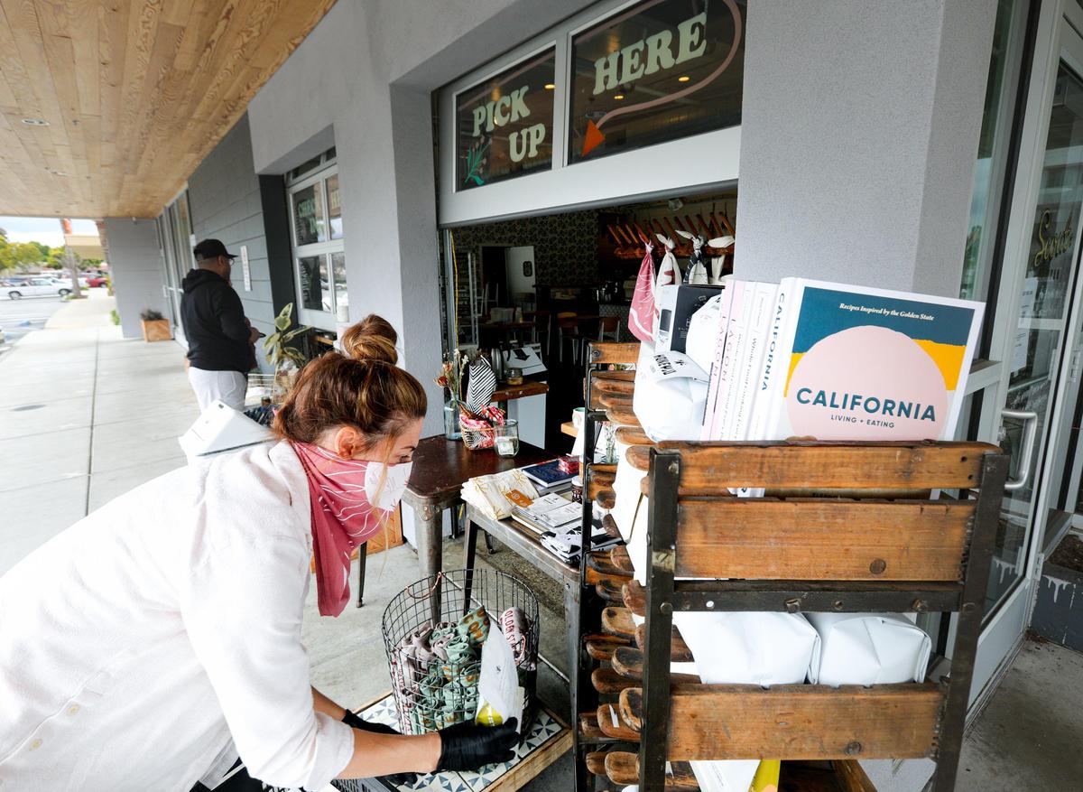 Sara Peterson, co-owner of Scout Coffee, stocks outdoor merchandise shelves next to a pickup window. Scout’s owners are coming up with creative ways to keep the San Luis Obispo coffee shop afloat during the coronavirus outbreak.